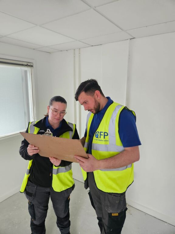 Q Fire Protection workers looking at a large clipboard to plan a fire protection install