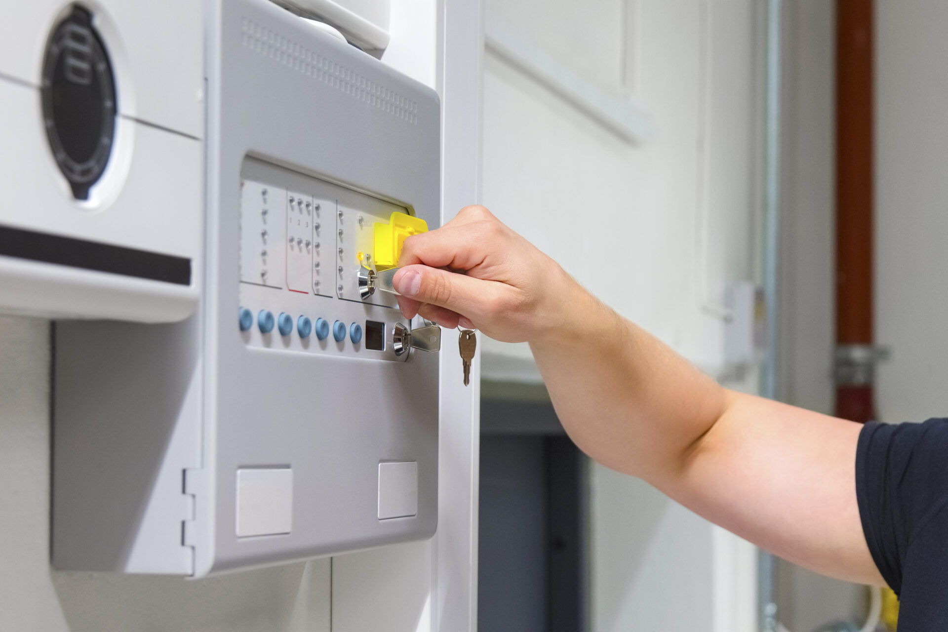 Close-up of male service technician opening fire panel in server room