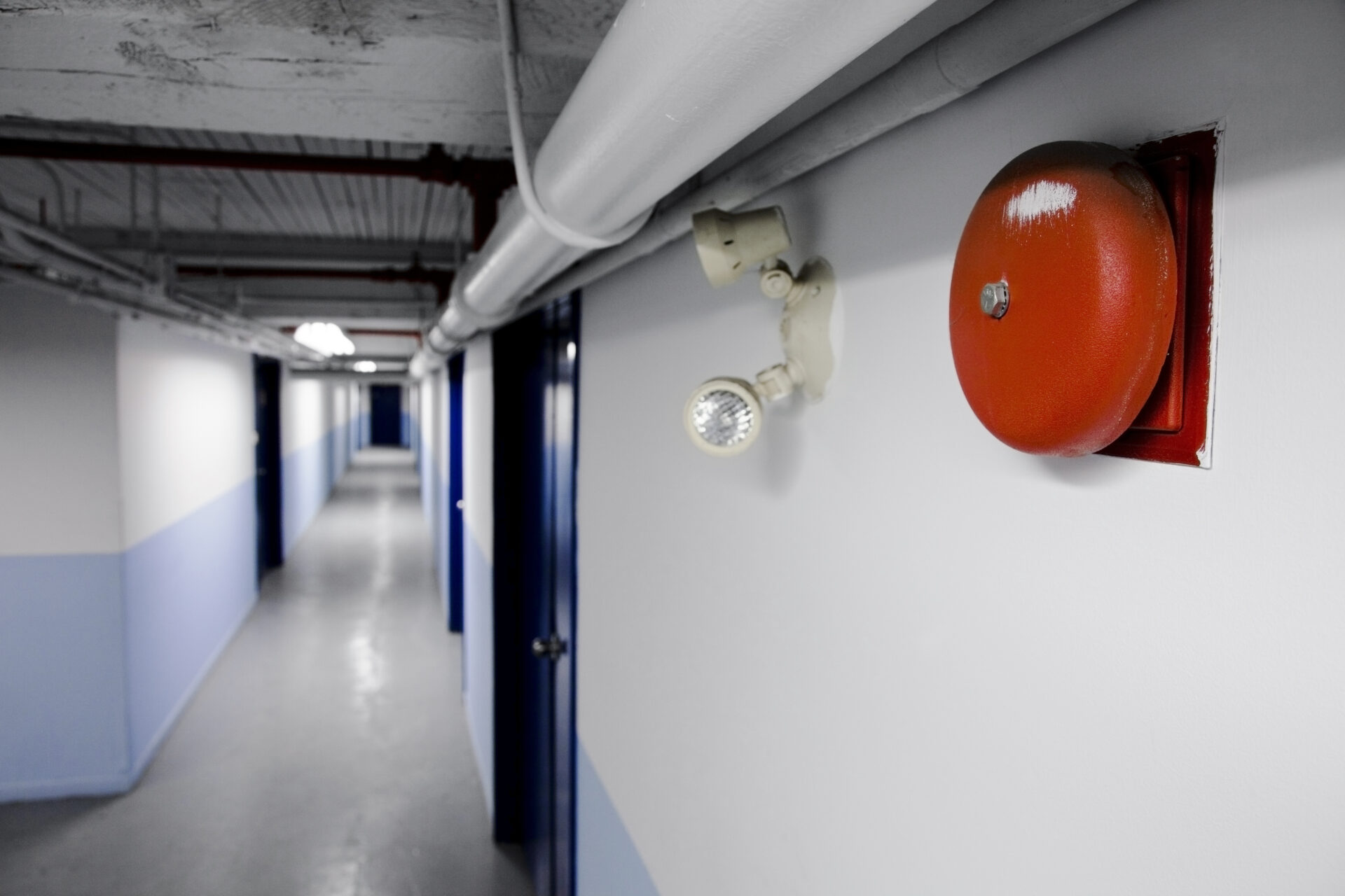 Fire Bell Alarm (red) with emergency light too in a long blue corridor illustration of a fire protection system design